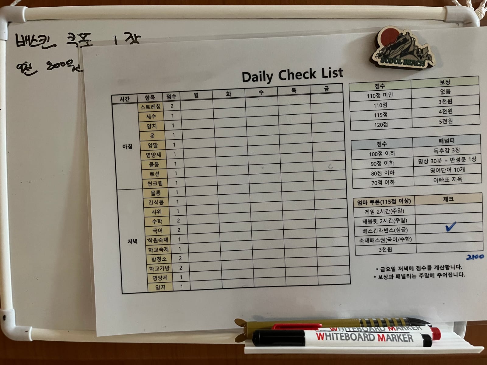벽에 건 흰색 화이트보드. 가운데에 코팅한 Daily Check List 표가 자석 하나로 붙어 있고, 그 왼쪽 빈 면에 검은 보드마카 손글씨로 두 줄이 적혀 있다. 아래 펜 트레이에 빨간 보드마카와 검은 보드마카가 놓여 있다.